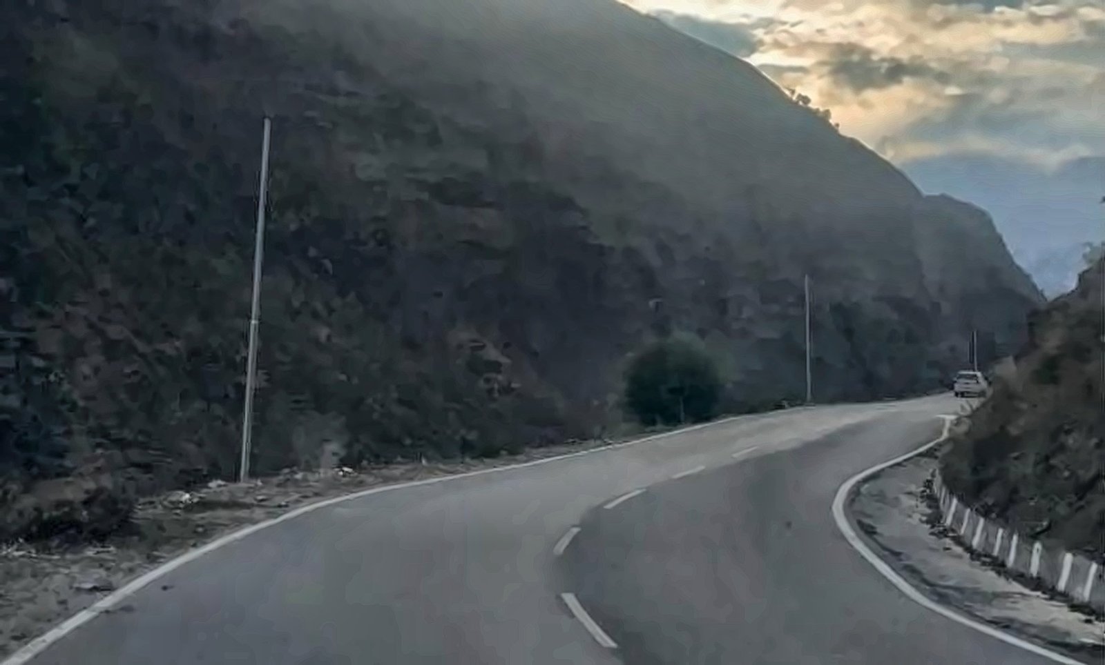 Winding road under a dark mountain at sunset