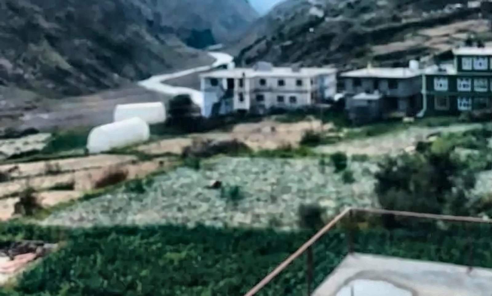 Mountain village with green fields and a river below